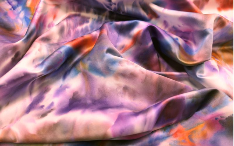 Для статьи о том, как покрасить ткань из полиэстера, на земле лежит многоцветная ткань.