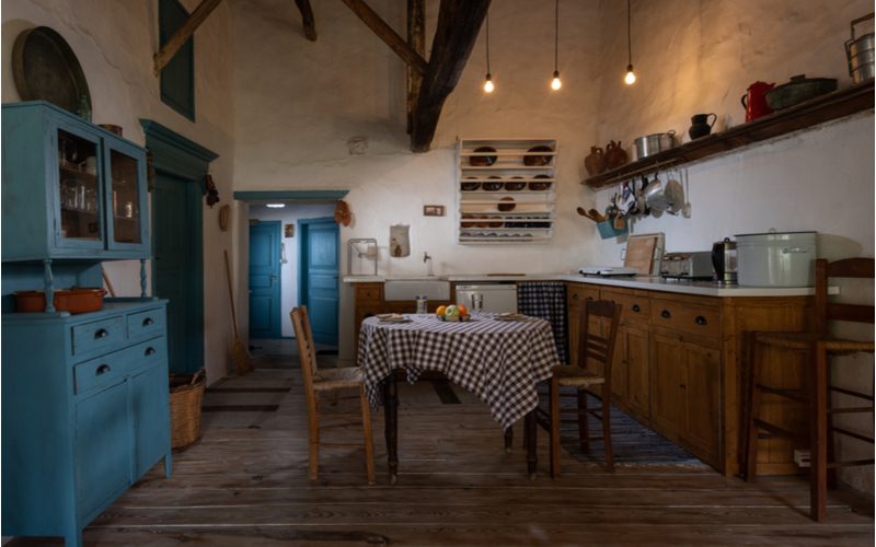 Кухня с деревенскими шкафами и эстетикой дуба и деревенского очарования с бирюзовой клеткой и открытыми деревянными балками
