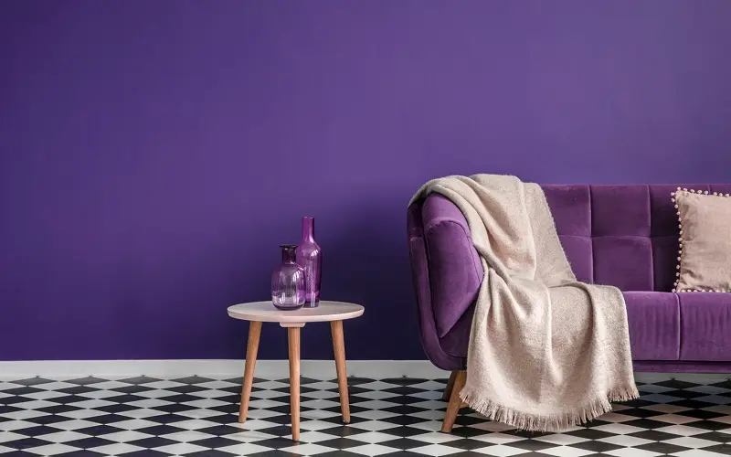 Фиолетовый диван с кремовым одеялом и подушками