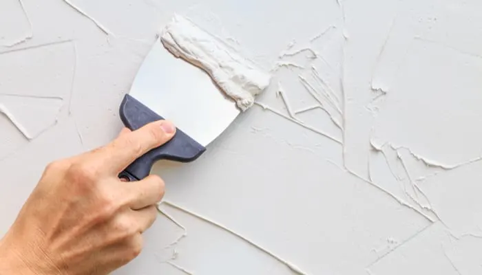 Рука с лопаточкой, чтобы добавить текстуру стены.